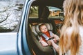 Baby in car mother fastens belts of safety car seat