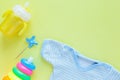 Baby care accessories and clothing background: baby jumpsuit, bottle, pyramid and toys on yellow background Royalty Free Stock Photo
