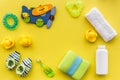 Baby care accessories, toys and clothing on yellow background top view mock up Royalty Free Stock Photo