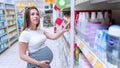 Baby care products pregnancy woman shopping. Young pregnant woman buying on baby bath shampoo bottle on supermarket Royalty Free Stock Photo