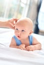 Baby Care. Young mother with little son lying on bed at home touching his head calming down close-up Royalty Free Stock Photo