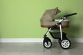 Baby carriage. Modern pram near light green wall, space for text