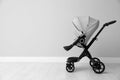 Baby carriage. Modern pram near light grey wall, space for text Royalty Free Stock Photo