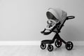 Baby carriage. Modern pram near light grey wall, space for text Royalty Free Stock Photo