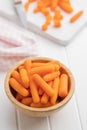 Baby carrot vegetable in bowl. Mini orange carrots on white table