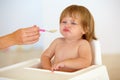 Baby, chair and eating food or unhappy mood for health meal, childhood development or upset. Hand, spoon and feed seat