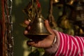 A BABY CHILD GIRL HAND TOUCHES A BIG BRASS BELL