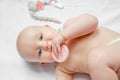 Baby child lying on belly weared with teether in mouth on white background. concept teething babies