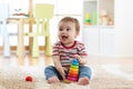 Baby child playing with educational pyramid toys at home. Little kid have fun indoors Royalty Free Stock Photo