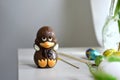 A baby chocolate duck on a table with some Easter eggs