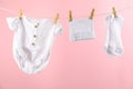 Baby clothes and accessories hanging on washing line against pink background Royalty Free Stock Photo