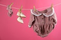 Baby clothes and accessories hanging on washing line against pink background Royalty Free Stock Photo