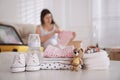 Baby clothes with accessories on white table and pregnant woman packing suitcase for maternity hospital indoors Royalty Free Stock Photo