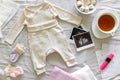 Baby clothes, calendar with the expected date of birth of baby, tea and ultrasound scan, pregnancy and birth concept