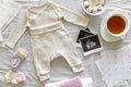 Baby clothes, calendar with the expected date of birth of baby, tea and ultrasound scan, pregnancy and birth concept