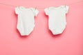 Baby clothes on a clothesline on pink background. twins