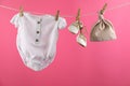 Baby clothes hanging on washing line against pink background Royalty Free Stock Photo