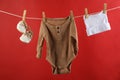 Baby clothes hanging on washing line against red background Royalty Free Stock Photo