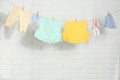 Baby clothes hanging on washing line near white brick wall Royalty Free Stock Photo