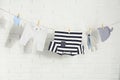 Baby clothes hanging on washing line near white brick wall Royalty Free Stock Photo