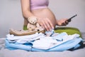 Baby clothes, necessities for mother and newborn in maternity bag. Pregnant woman getting ready for labor packing stuff for Royalty Free Stock Photo