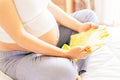 Baby clothes pregnant woman. Beautiful pregnancy mother with yellow baby clothes. Pregnant woman hugging belly and