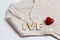 Baby clothes with wooden text IVF and heart. Concept - IVF, in vitro fertilization. Waiting for baby, pregnant