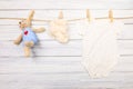 Baby clothes and  toy bear on a clothesline on wooden background  - Image Royalty Free Stock Photo