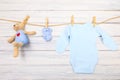 Baby clothes and  toy bear on a clothesline on wooden background  - Image Royalty Free Stock Photo