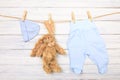 Baby clothes and  toy bunny on a clothesline on wooden background  - Image Royalty Free Stock Photo