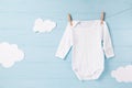 Baby clothes and white clouds on a clothesline, blue background Royalty Free Stock Photo