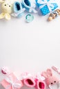 Top view vertical photo of pink and blue knitted booties gift boxes bunny toys wooden rattle and pacifiers Royalty Free Stock Photo