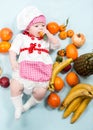 Baby cook girl wearing chef hat with fresh fruits. Royalty Free Stock Photo