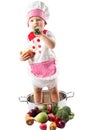 Baby cook girl wearing chef hat with fresh vegetables and fruits. Royalty Free Stock Photo