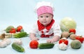 Baby cook girl wearing chef hat with fresh vegetables. Royalty Free Stock Photo