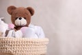 Baby cosmetic products, bath accessories and toy bear in knitted basket on beige background, closeup. Space for text Royalty Free Stock Photo