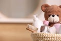 Baby cosmetic products, bath accessories and toy bear in knitted basket indoors, closeup. Space for text Royalty Free Stock Photo