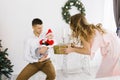 The baby in the costume of a little Santa in dad`s arms, and mom gives him a Christmas gift in the living room Royalty Free Stock Photo