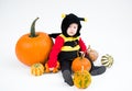 Baby in costume with pumpkins on white background