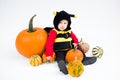 Baby in costume with pumpkins on white background