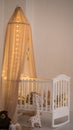 Baby cot with New Year`s decor. A toy giraffe next to a crib. Small tree in the children`s room.