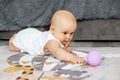 Baby creep on floor of nursery grabbing colorful ball. Baby development. Sensory experience