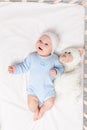 Baby in the crib, laughing baby 3 months lying with a teddy bear toy, children and birth concept Royalty Free Stock Photo