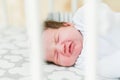 Baby in the crib. Newborn baby boy in bed. New born child sleeping under a white knitted blanket. Children sleep. Bedding for kids Royalty Free Stock Photo