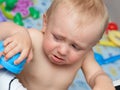 Baby cries holding a toy