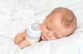 Baby curled up sleeping on a blanket with feeding bottle Royalty Free Stock Photo