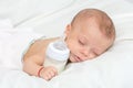Baby curled up sleeping on a blanket with feeding bottle Royalty Free Stock Photo