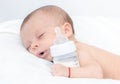 Baby curled up sleeping on a blanket with feeding bottle Royalty Free Stock Photo