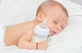 Baby curled up sleeping on a blanket with feeding bottle Royalty Free Stock Photo