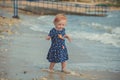 Baby cute girl with blond hair and pink apple cheek enjoying summer time holiday posing in beautiful beach full of sand wearing st Royalty Free Stock Photo